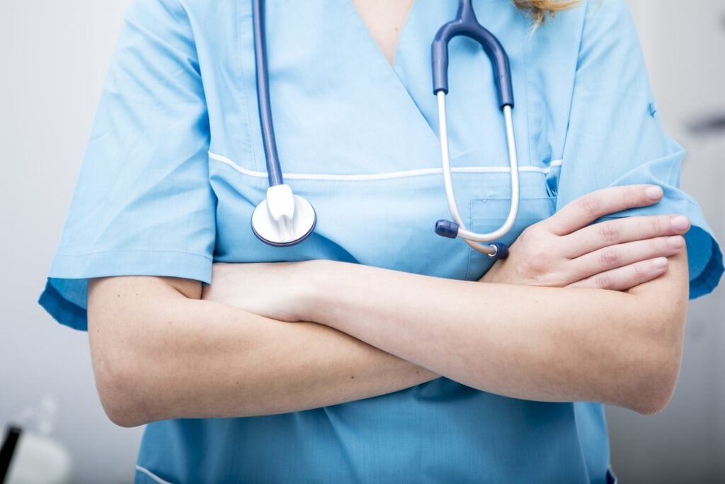 Healthcare professional in scrubs with stethoscope for medical safety and health services.